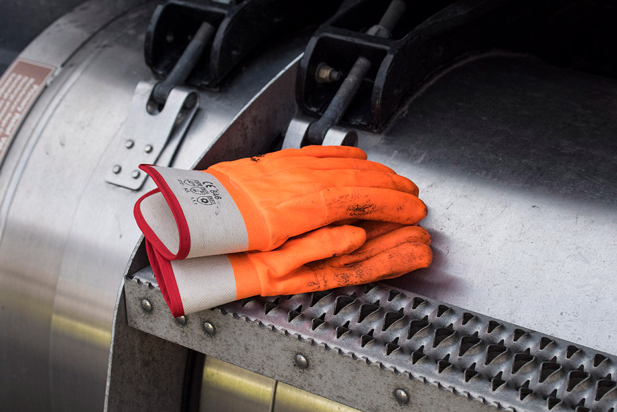 A pair of orange working gloves sits on a piece of heavy duty machinery