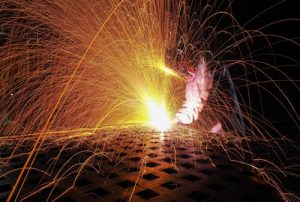 Welding torch creates sparks against metal in the welding process