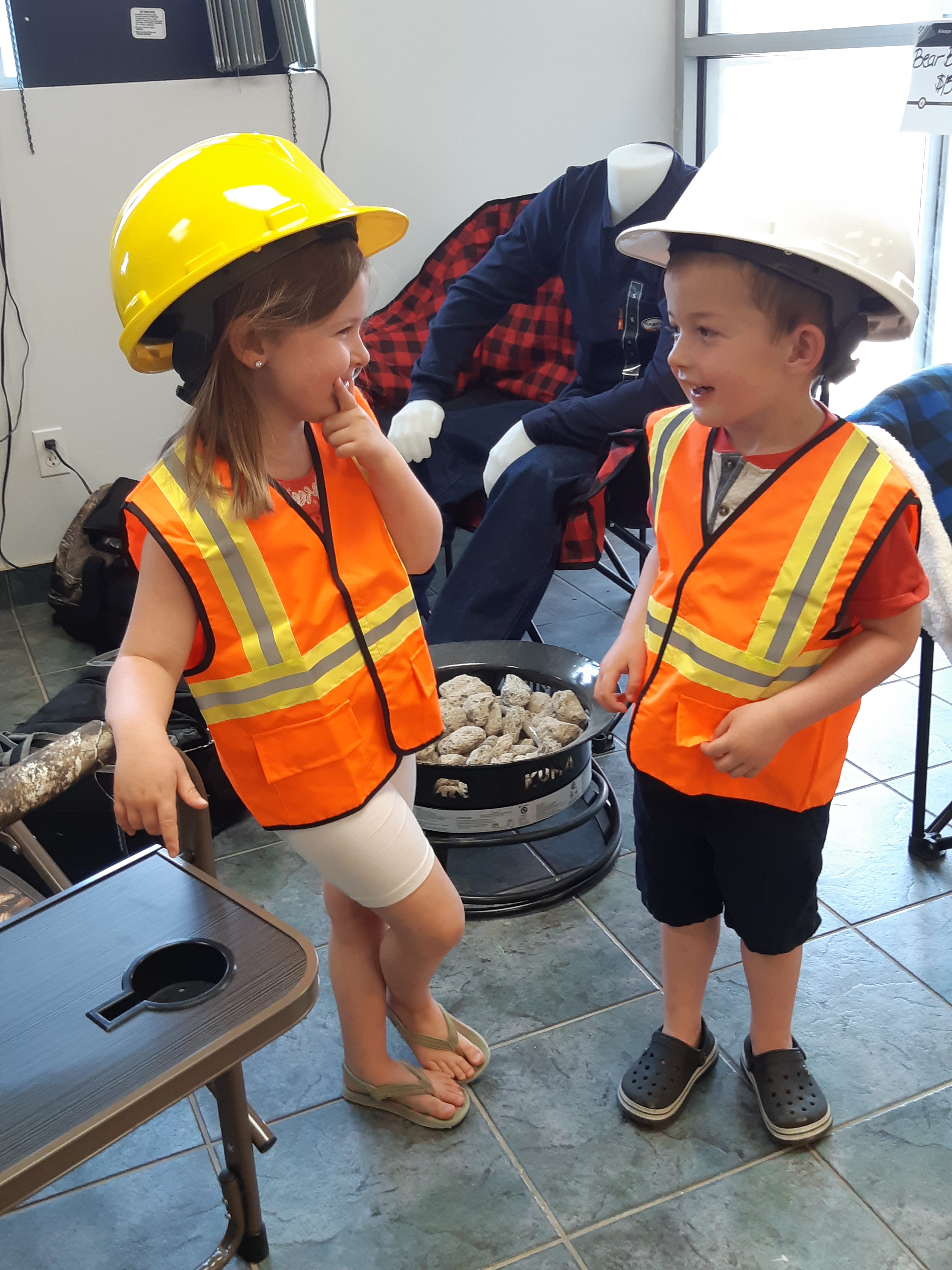 Two children in orange hi viz safety vests and hardhats